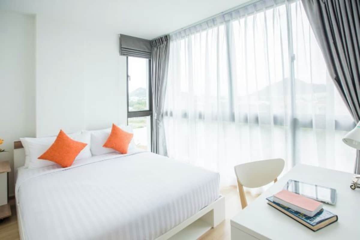 A hotel room with a bed, a desk, and a chair.