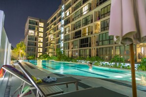 A modern hotel with a swimming pool, multiple balconies, and outdoor seating areas. - Connext Residence Phuket (Phuket)