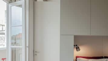 A bedroom with a bed, a wardrobe, and a door leading to a balcony.