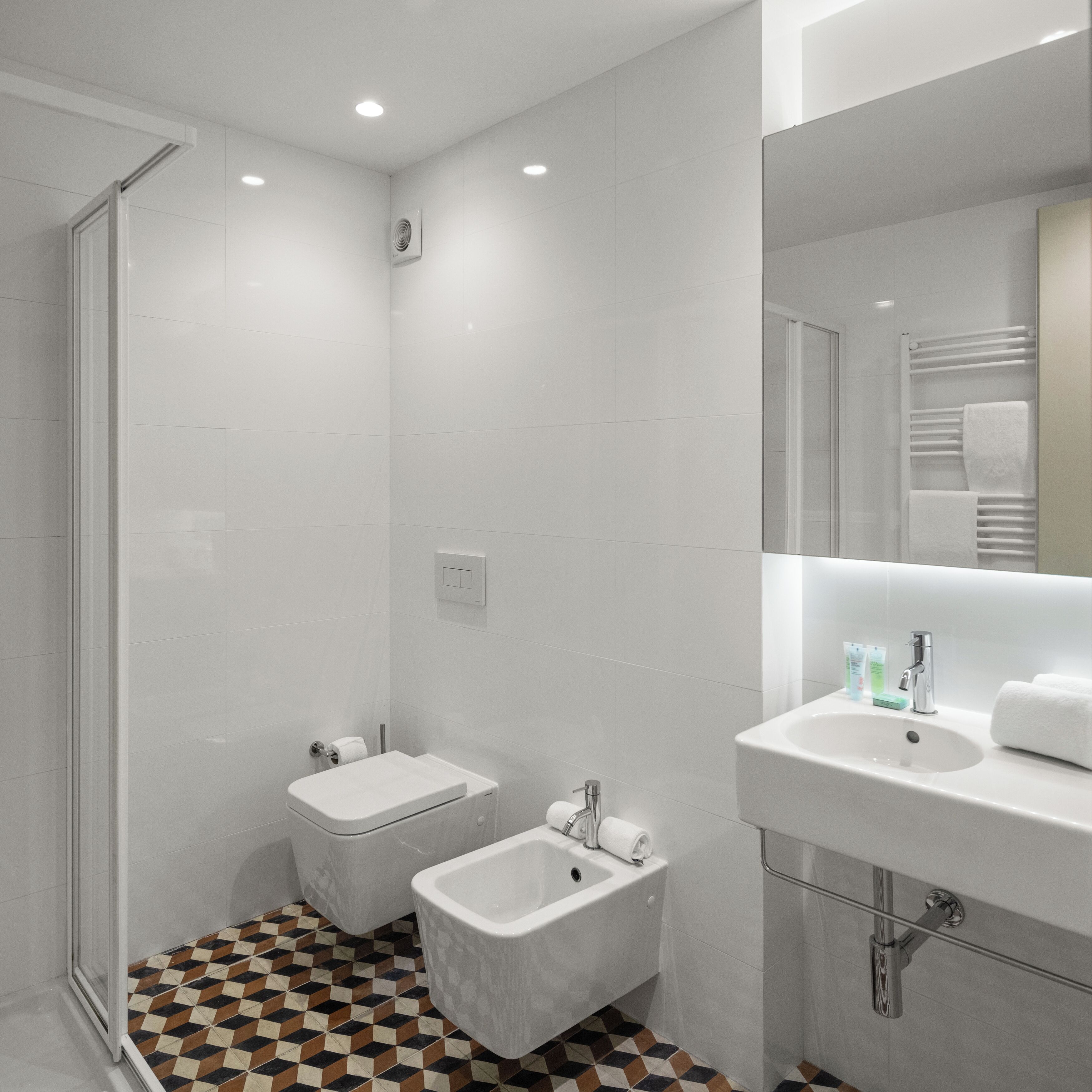 A modern bathroom with a shower, toilet, bidet, and sink.