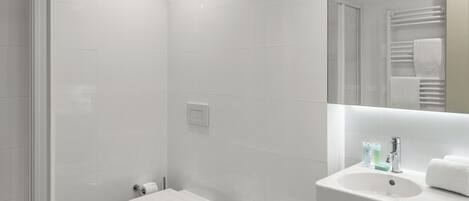 A modern bathroom with a shower, toilet, bidet, and sink.