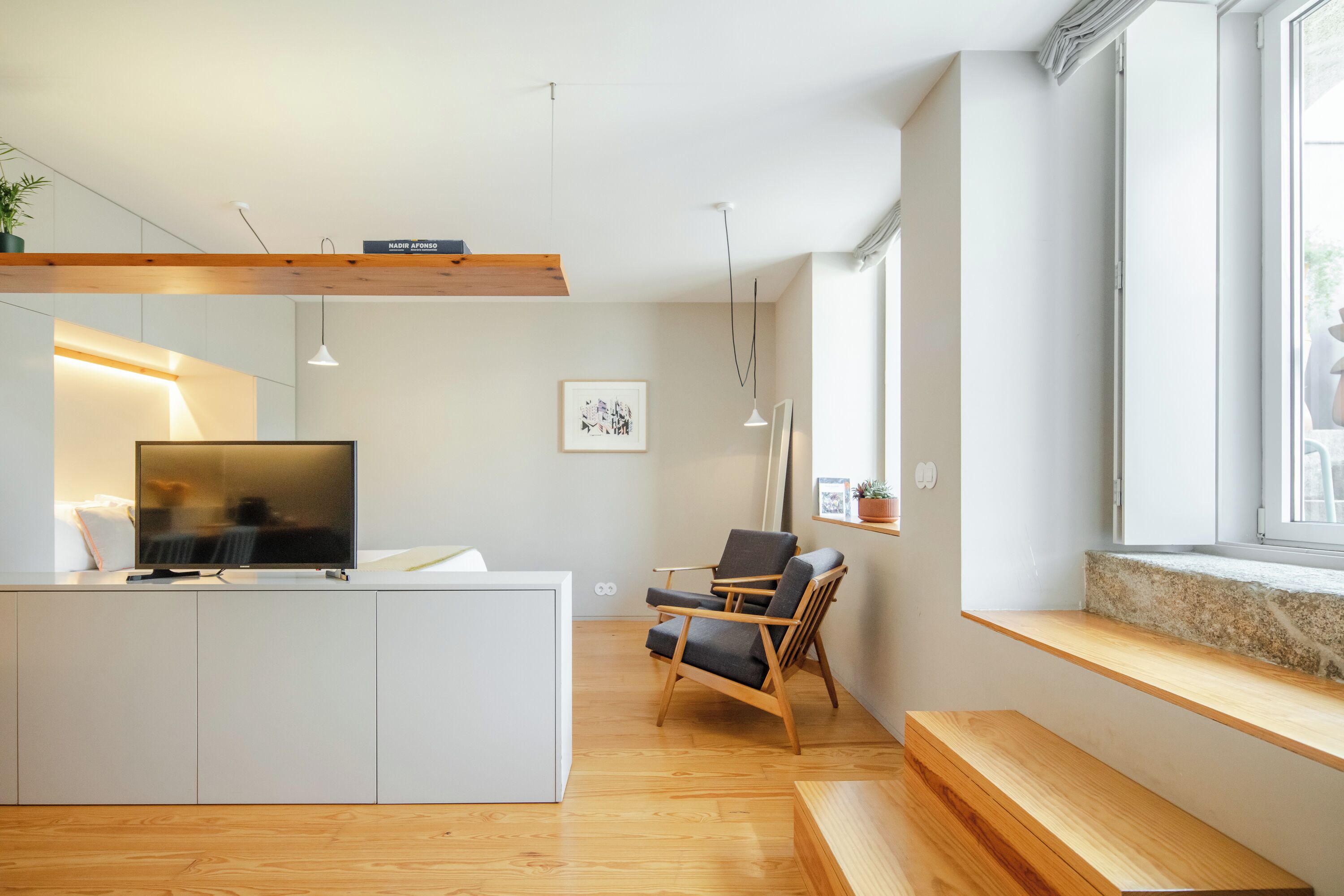 A modern living room with a TV, wooden furniture, and a large window.