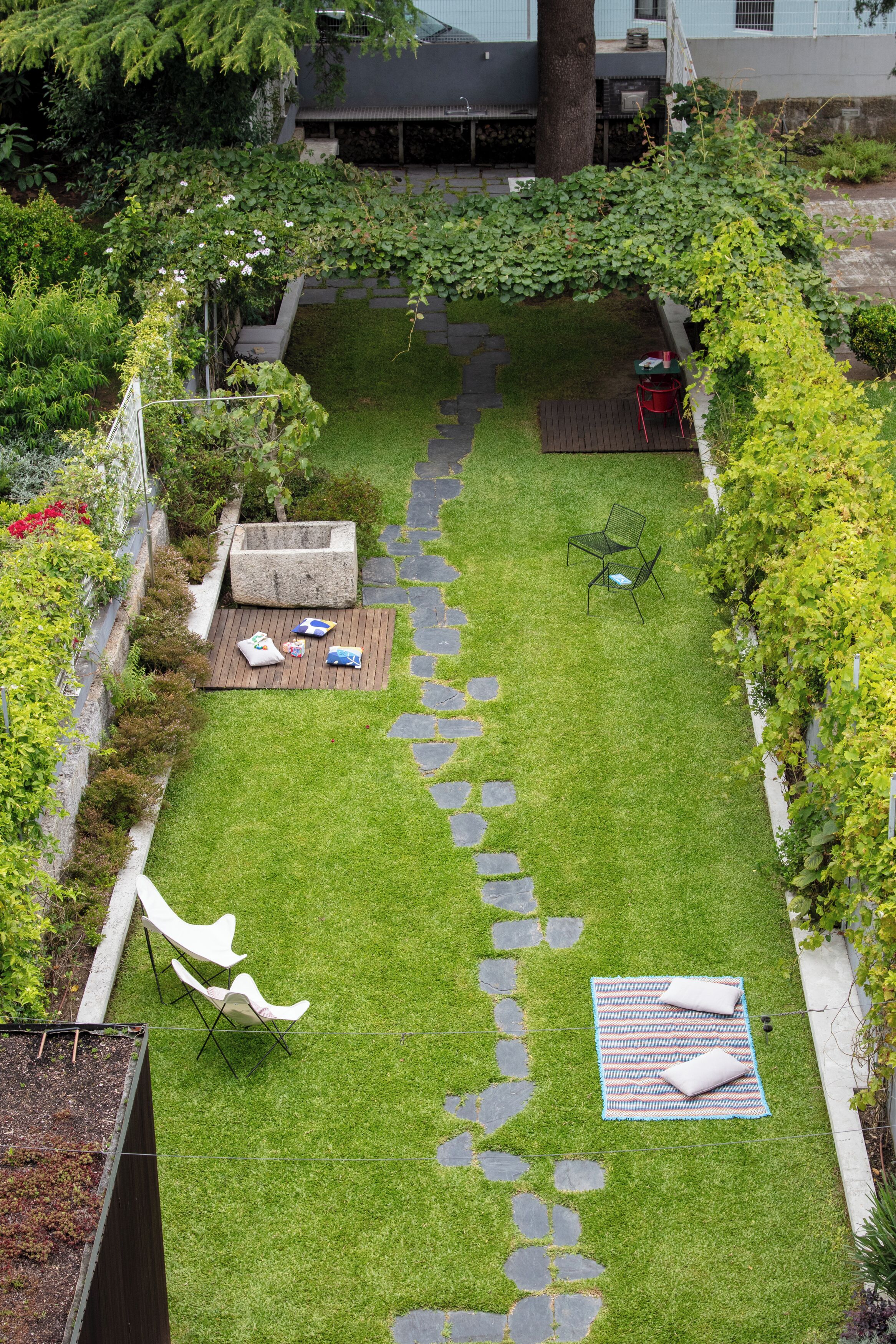 A well-maintained garden with a stone pathway, a wooden deck, and outdoor seating.