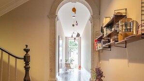 A hallway with a wooden bench, a vase with flowers, and a shelf with jars. - Baumhaus Serviced Living - Art & Design Apartments (Porto)