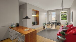 A modern kitchen with a wooden countertop, white cabinets, and a dining area with a red sofa and a small table. - Baumhaus Serviced Living - Art & Design Apartments (Porto)