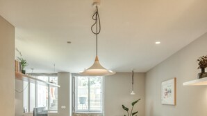A modern kitchen with a central island, wooden chairs, a dining table, and pendant lighting. - Baumhaus Serviced Living - Art & Design Apartments (Porto)
