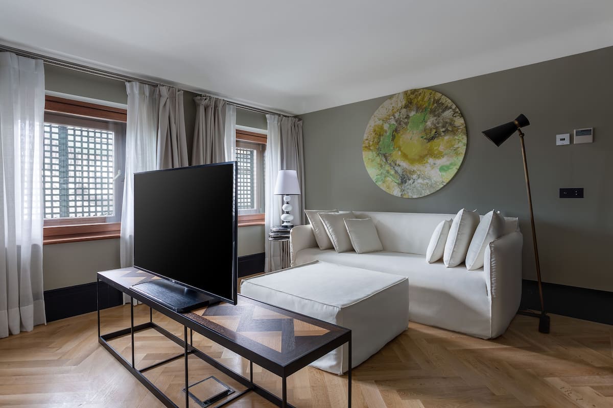 Un salon moderne avec un téléviseur à écran plat, un canapé blanc, une table basse et un lampadaire.