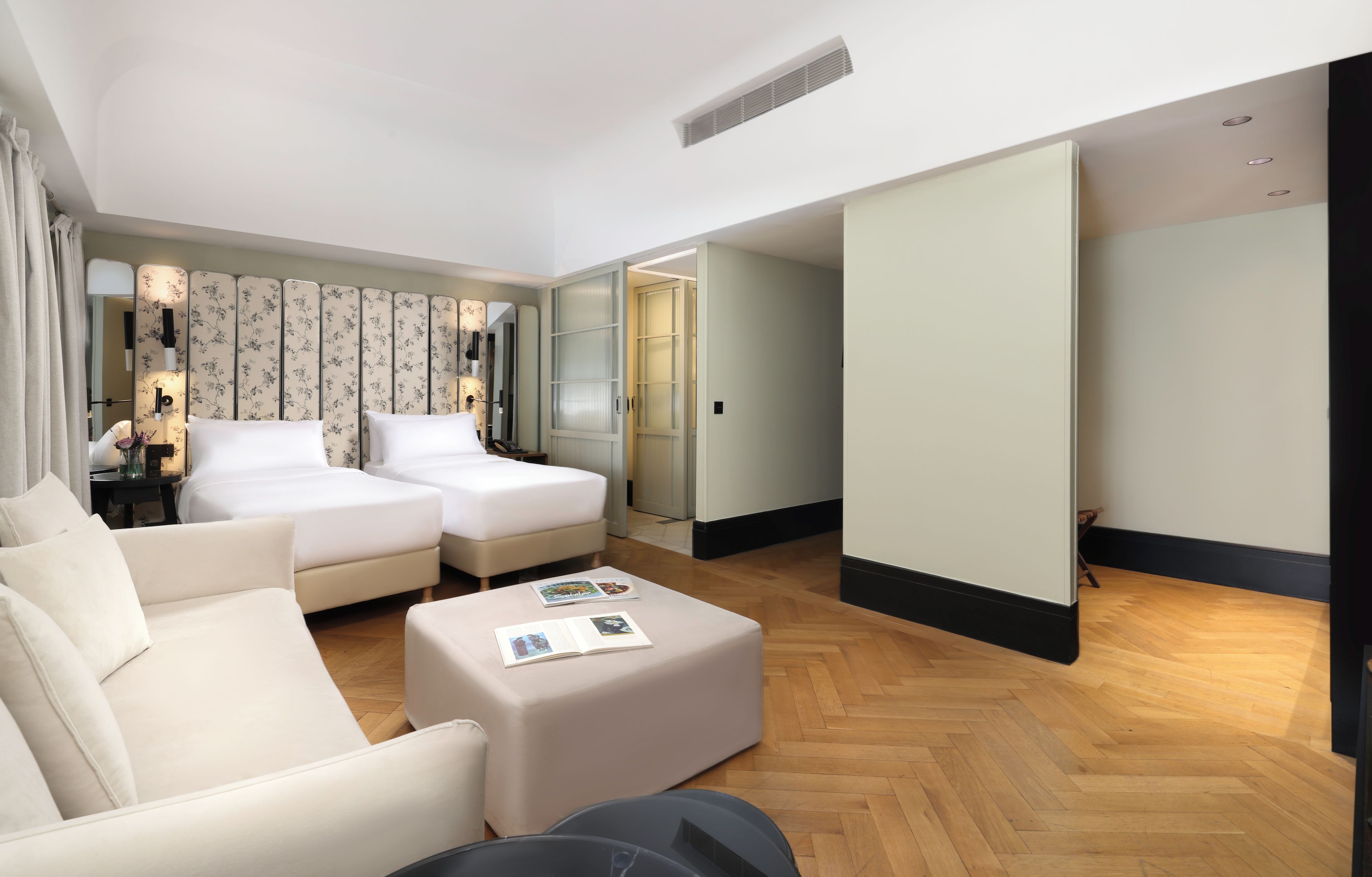 Una habitación de hotel con un sofá, dos camas, una mesita de café y un espejo.