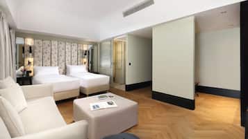Una habitación de hotel con un sofá, dos camas, una mesita de café y un espejo.