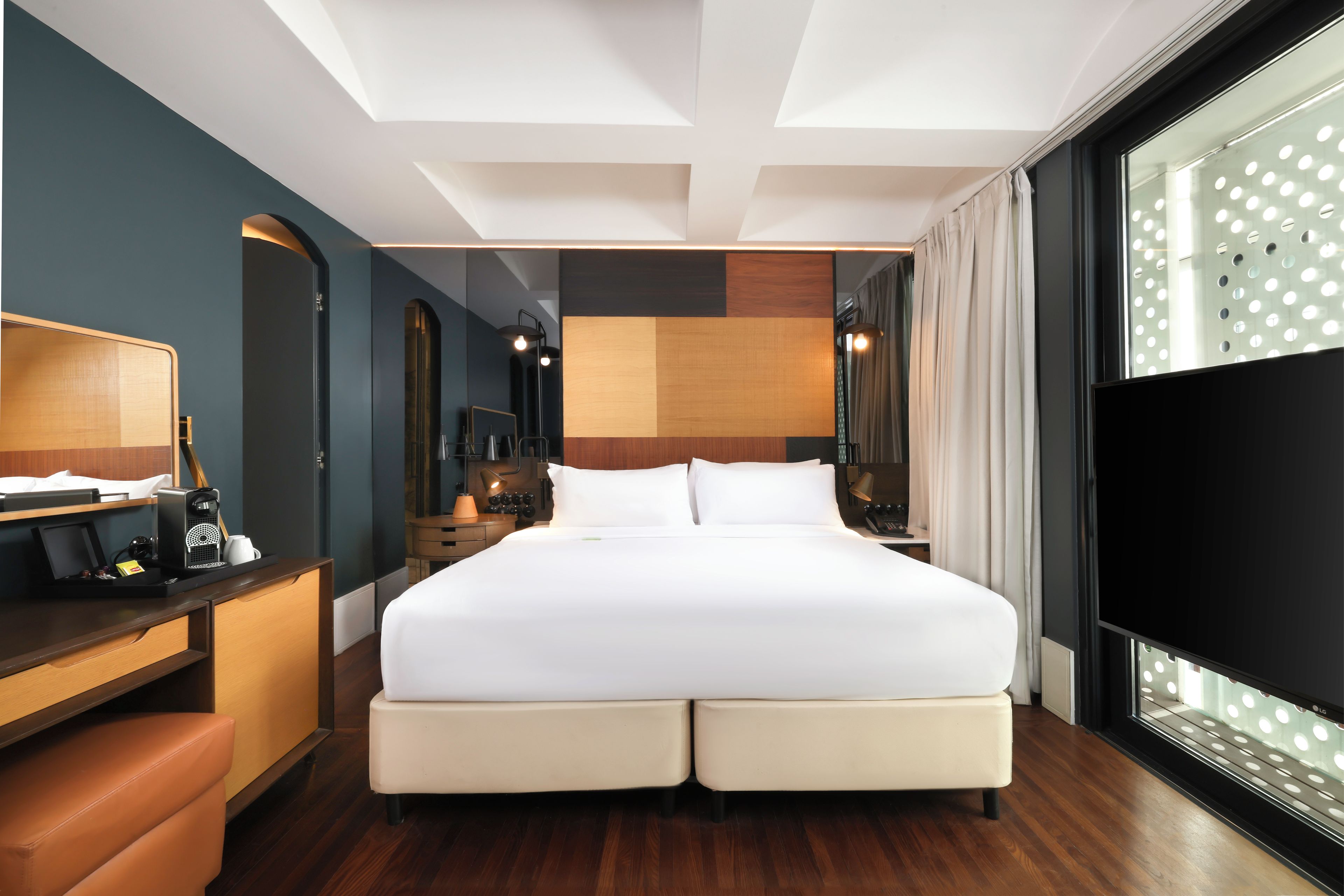 Una habitación de hotel con una cama grande, un escritorio con una silla, un televisor y una ventana con cortina.