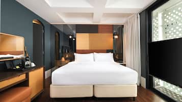 A hotel room with a large bed, a desk with a chair, a TV, and a window with a curtain.