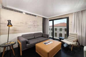 A modern living room with a grey sofa, a brown ottoman, a floor lamp, and a chair. - The Wings Hotels Collection (Istanbul)