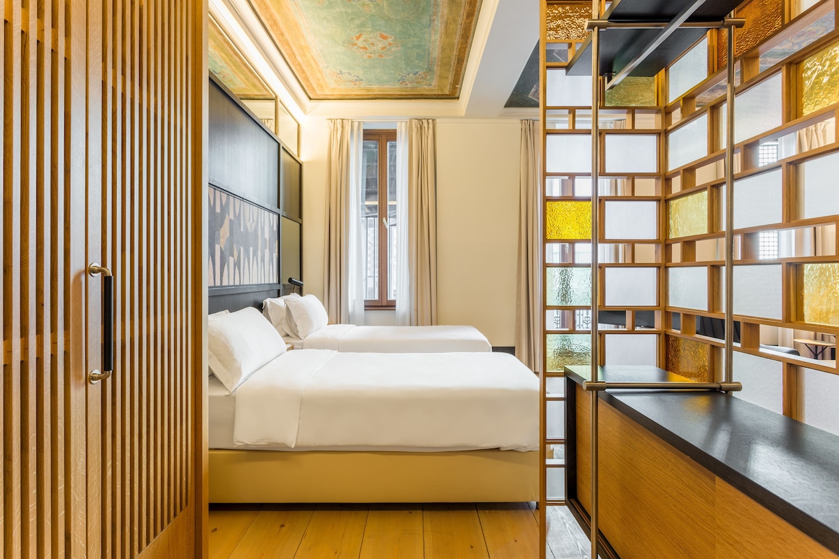 Une chambre d’hôtel avec un lit, une armoire, une fenêtre et un mur décoratif.