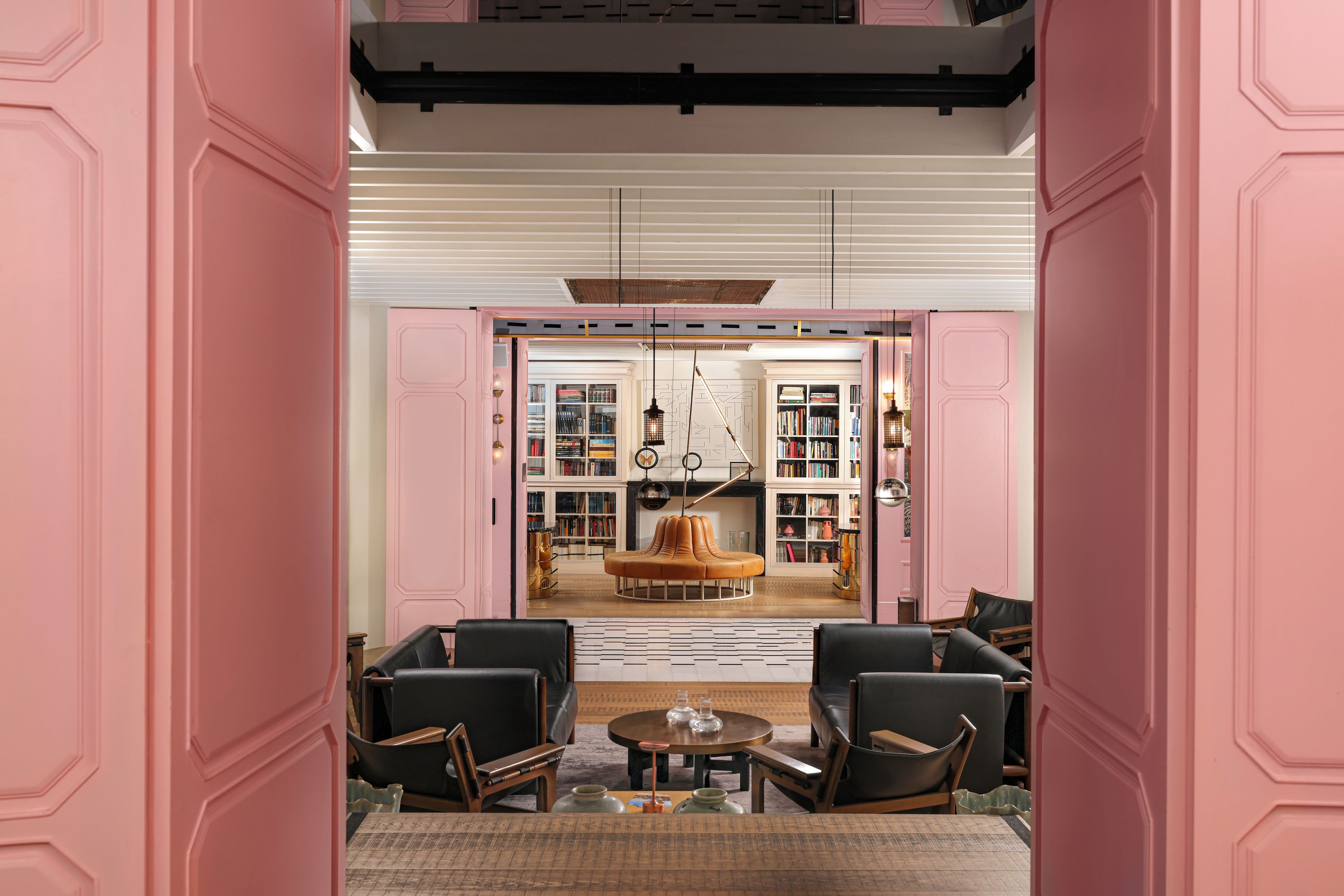 A room with a central seating area, a bookshelf, and a ceiling with a unique design.