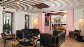 Un interior moderno con un sofá de cuero negro, sillas de madera, una mesa de centro y una pared de acento rosa.