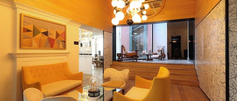 A modern interior with a wooden ceiling, a geometric art piece, and a seating area with a glass coffee table.