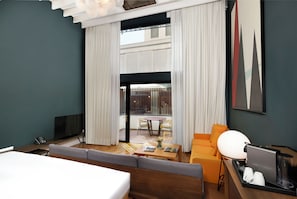Une chambre d’hôtel moderne équipée d’un canapé, d’une table basse, d’un téléviseur et d’un bureau avec une machine à café.