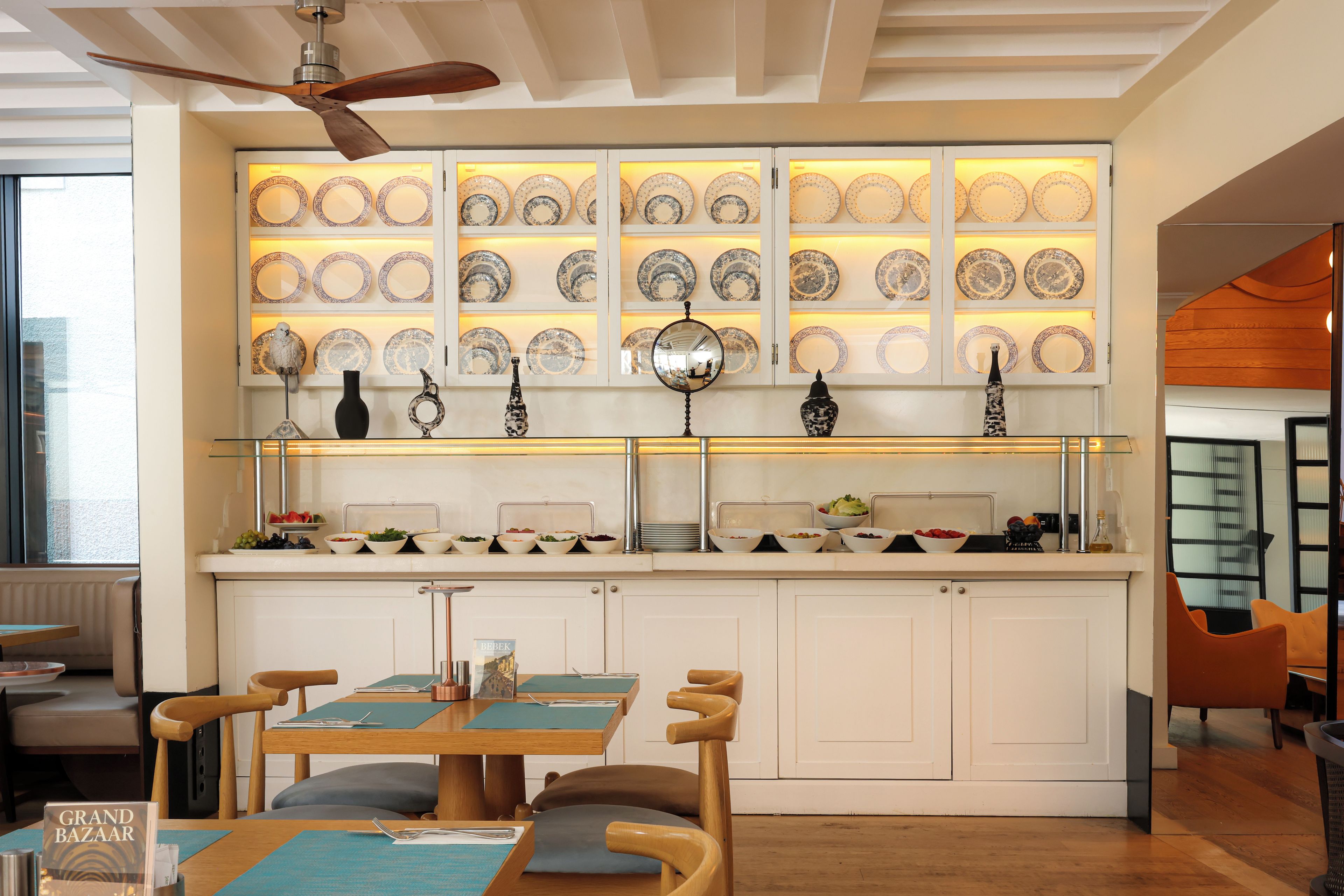 A modern kitchen with a central island, a dining area with chairs, and a wall of decorative plates.