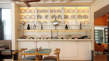 A modern kitchen with a central island, a dining area with chairs, and a wall of decorative plates.