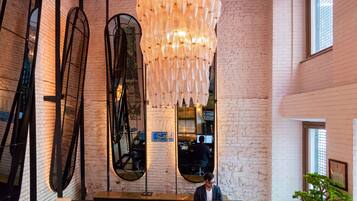 A reception area with a modern design, featuring a large chandelier, a round mirror, and a reception desk.