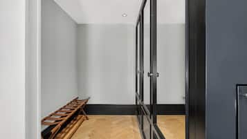 Una habitación con un banco de madera, una puerta negra y un piso con estampado tipo espiga.