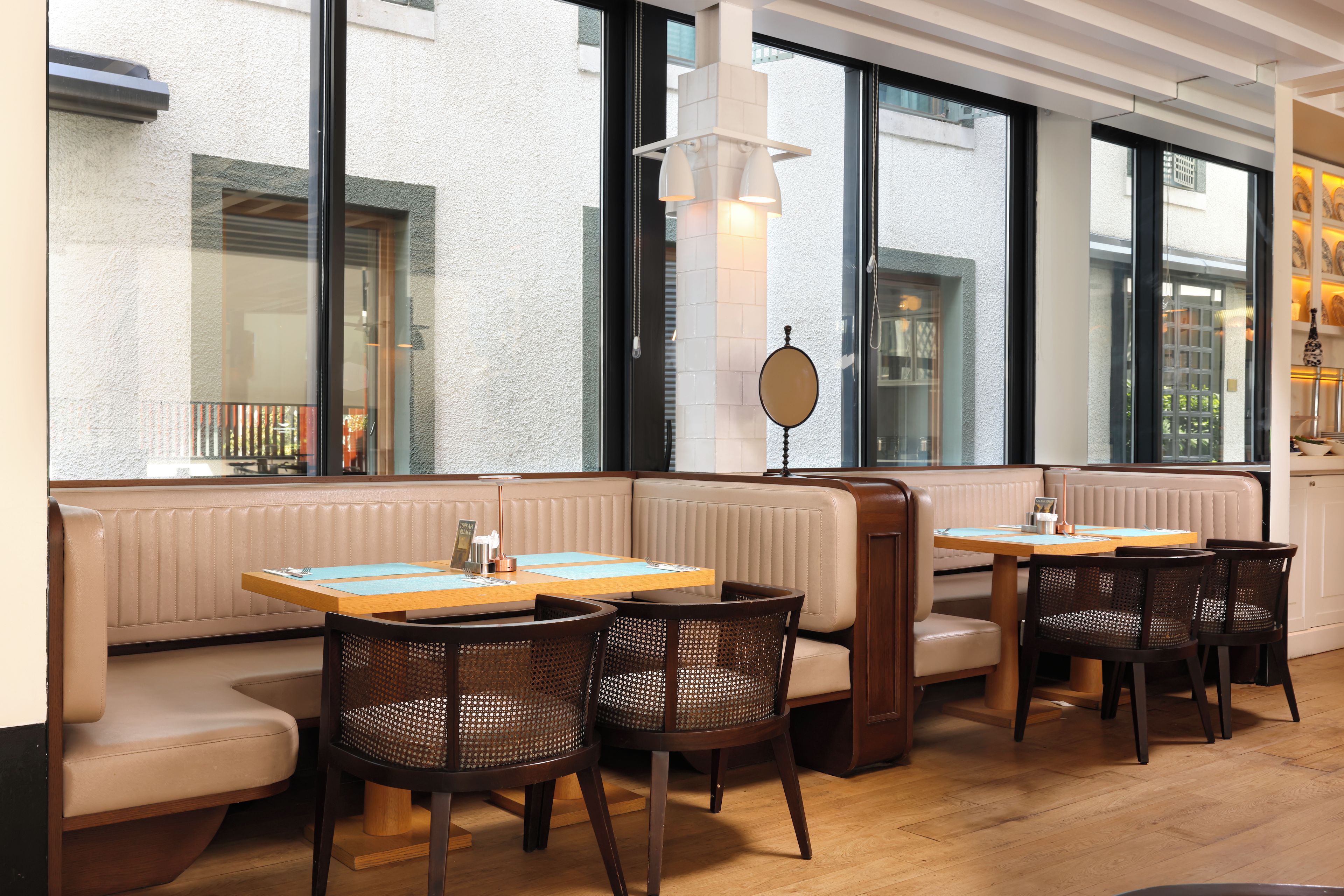 Un interior de restaurante con asientos tipo cabina, mesas de madera y sillas de mimbre.