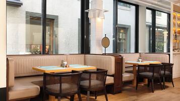 A restaurant interior with booth seating, wooden tables, and wicker chairs.