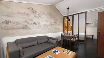 Una sala de estar moderna con un sofá gris, una mesa de comedor de madera con sillas, y un mural grande en la pared.