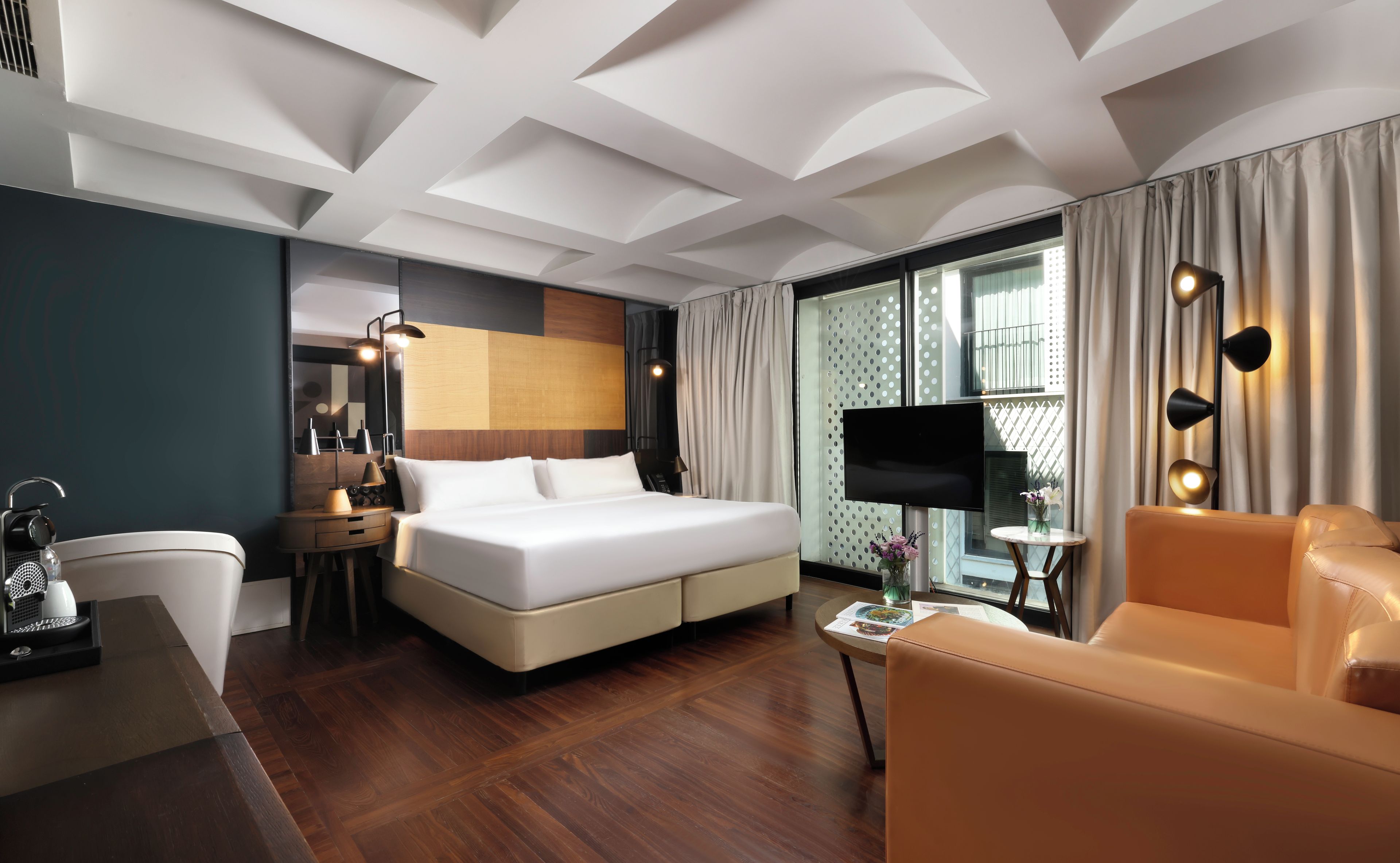 Ein Hotelzimmer mit einem Bett, einem Schreibtisch, einem Stuhl, einem Fernseher und einem Fenster mit Vorhängen.