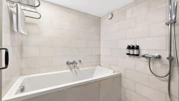 A modern bathroom with a bathtub, shower, and hand soap dispensers.