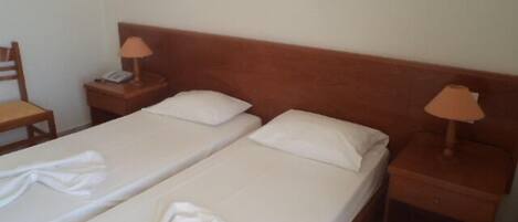 Una cama doble con sábanas blancas y dos mesitas de noche con lámparas.