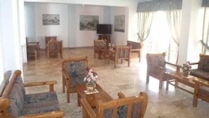 Un salón amplio con muebles de madera, un televisor y obras de arte en las paredes.
