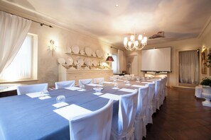 Ein Konferenzraum mit einem langen Tisch, weißen Stühlen, einer Projektionsleinwand und einer Kristallleuchtre.