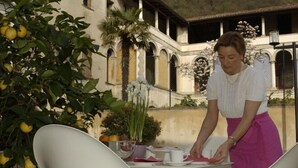 A person setting up a table outdoors with chairs and a tablecloth. - Hotel Dei Chiostri (Follina)