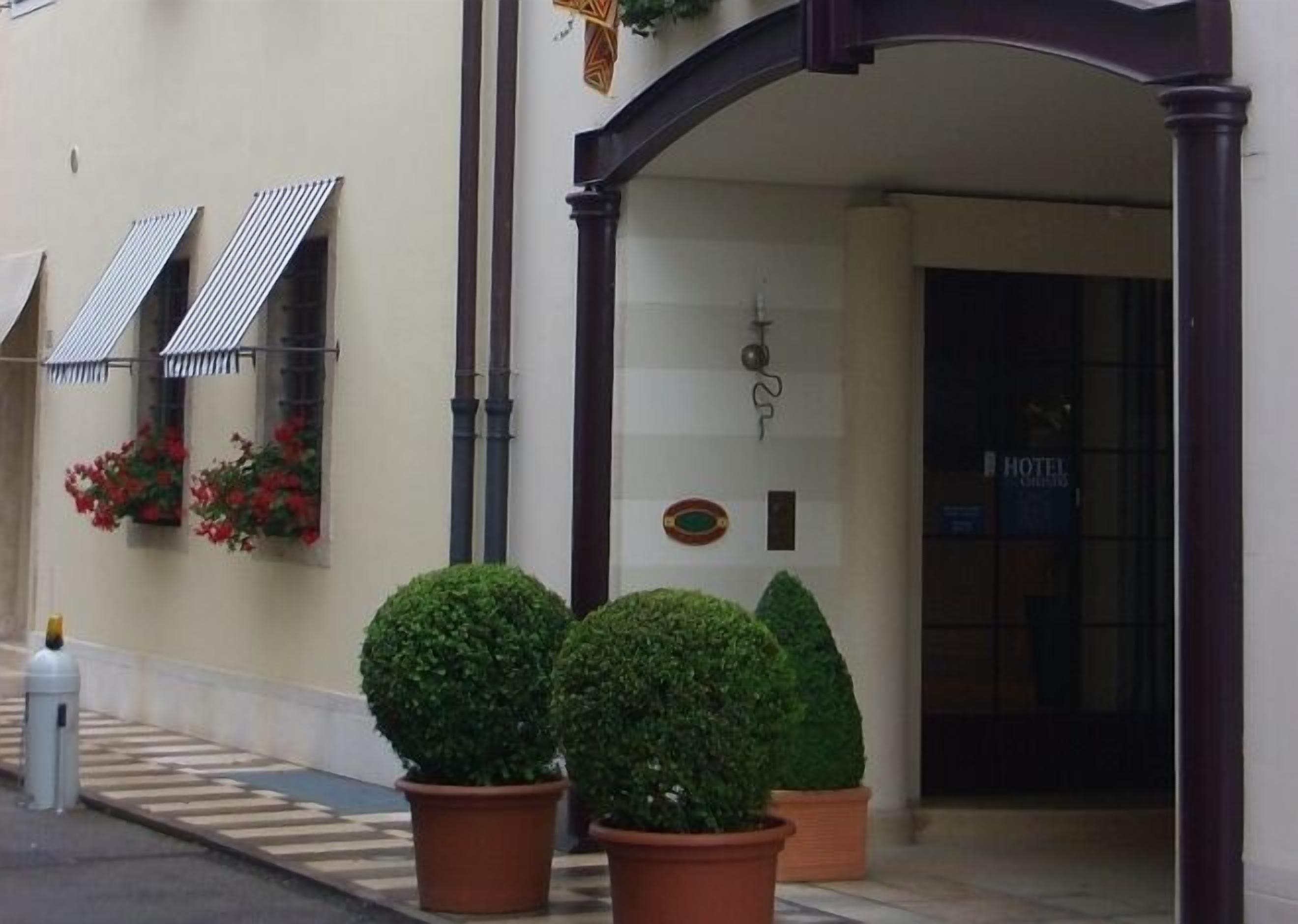 A hotel entrance with a dark archway, potted plants, and a sign indicating the hotel's name.
