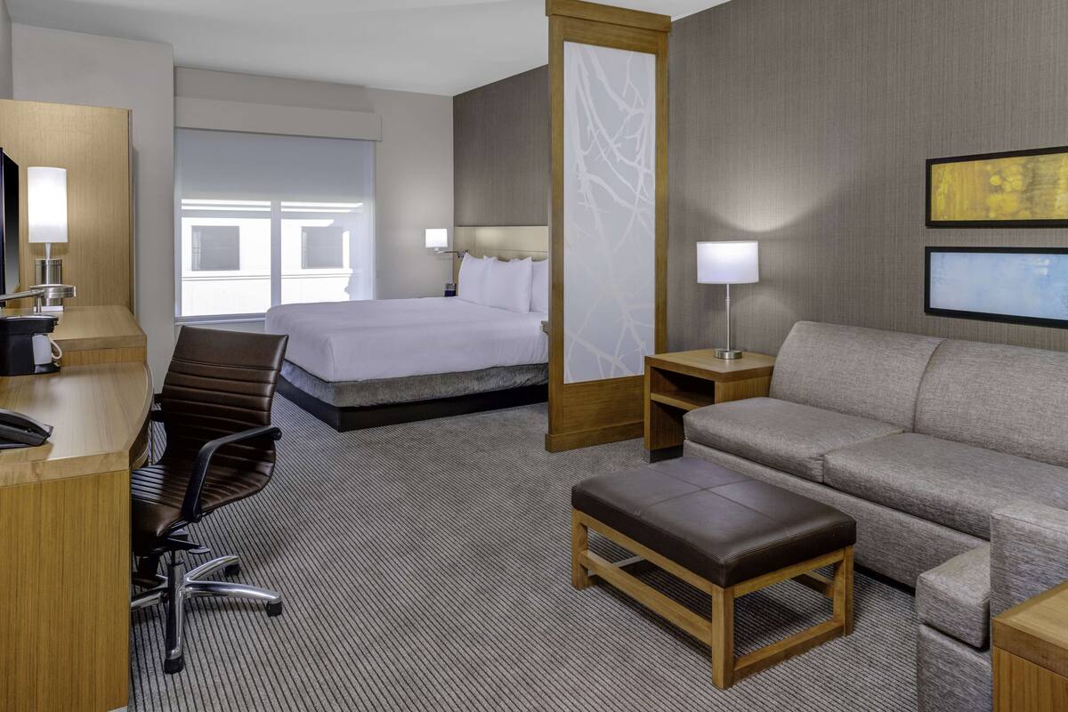 Ein Hotelzimmer mit Bett, Sofa, Schreibtisch und Stuhl.
