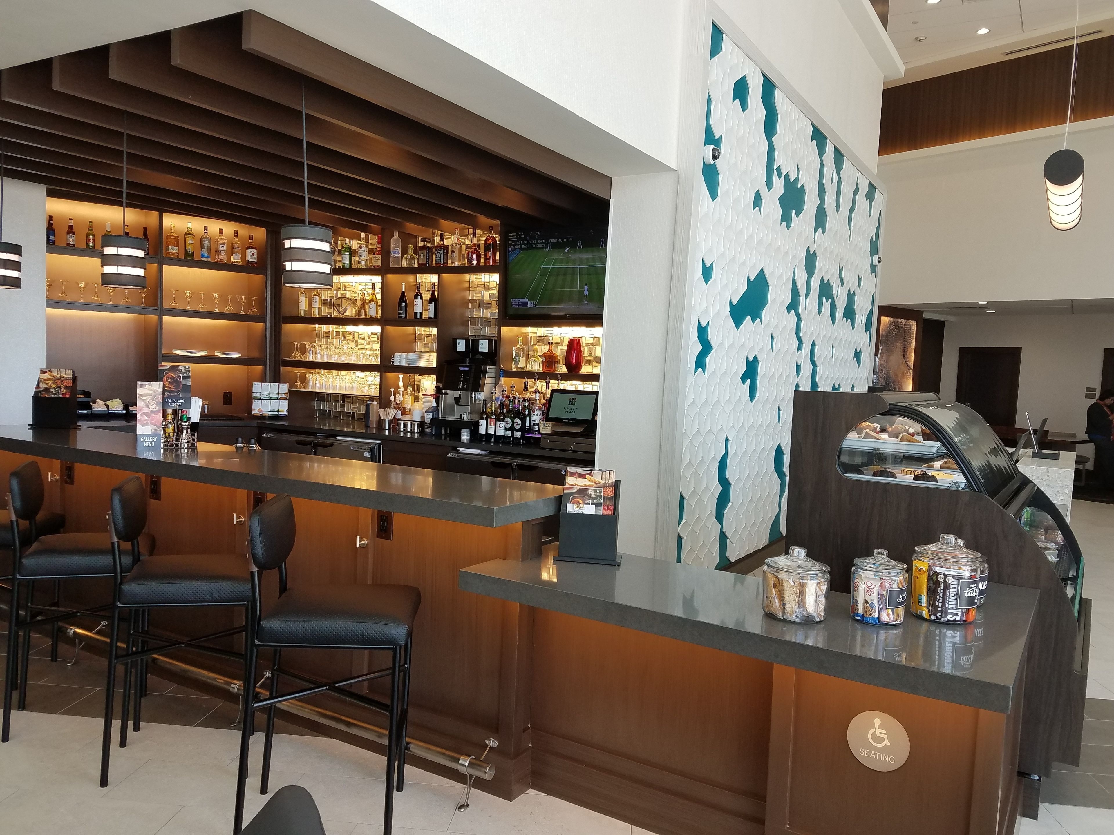 Een bar met een toonbank, zitplaatsen en een decoratieve muur.