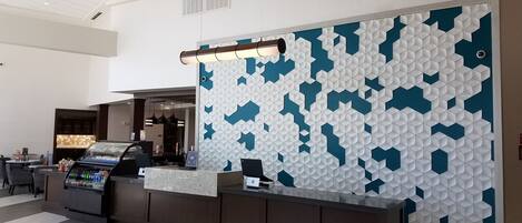 A reception area with a modern design, featuring a patterned wall and a counter with a beverage dispenser.