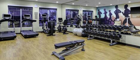 A gym with treadmills, weight machines, a bench, and dumbbells.