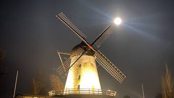A windmill at night with a bright moon in the background.