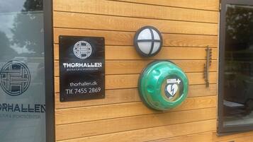 Pared de madera con un letrero del Centro Cultural y Deportivo Thorhallen Jels, un buzón y un buzón verde con un símbolo de corazón.