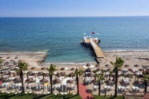 A beach resort with a pier extending into the sea, rows of sun loungers, and umbrellas. - Club Dizalya Hotel (Alanya)