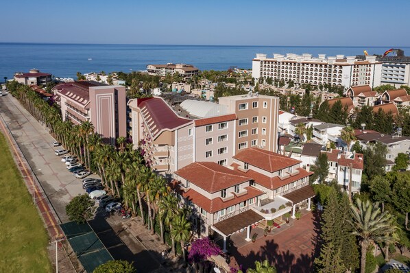 An aerial view of a coastal hotel complex with multiple buildings, a parking lot, and a beachfront view. - Club Dizalya Hotel (Alanya)