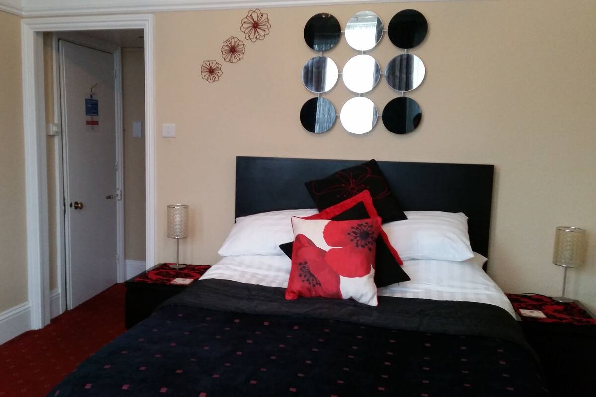A hotel room with a bed, a door, and wall decorations.