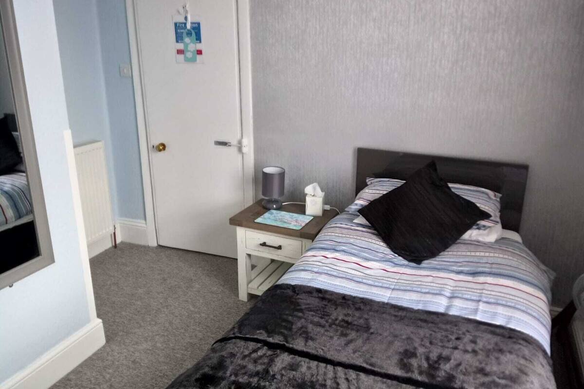A bedroom with a bed, bedside table, and a door.