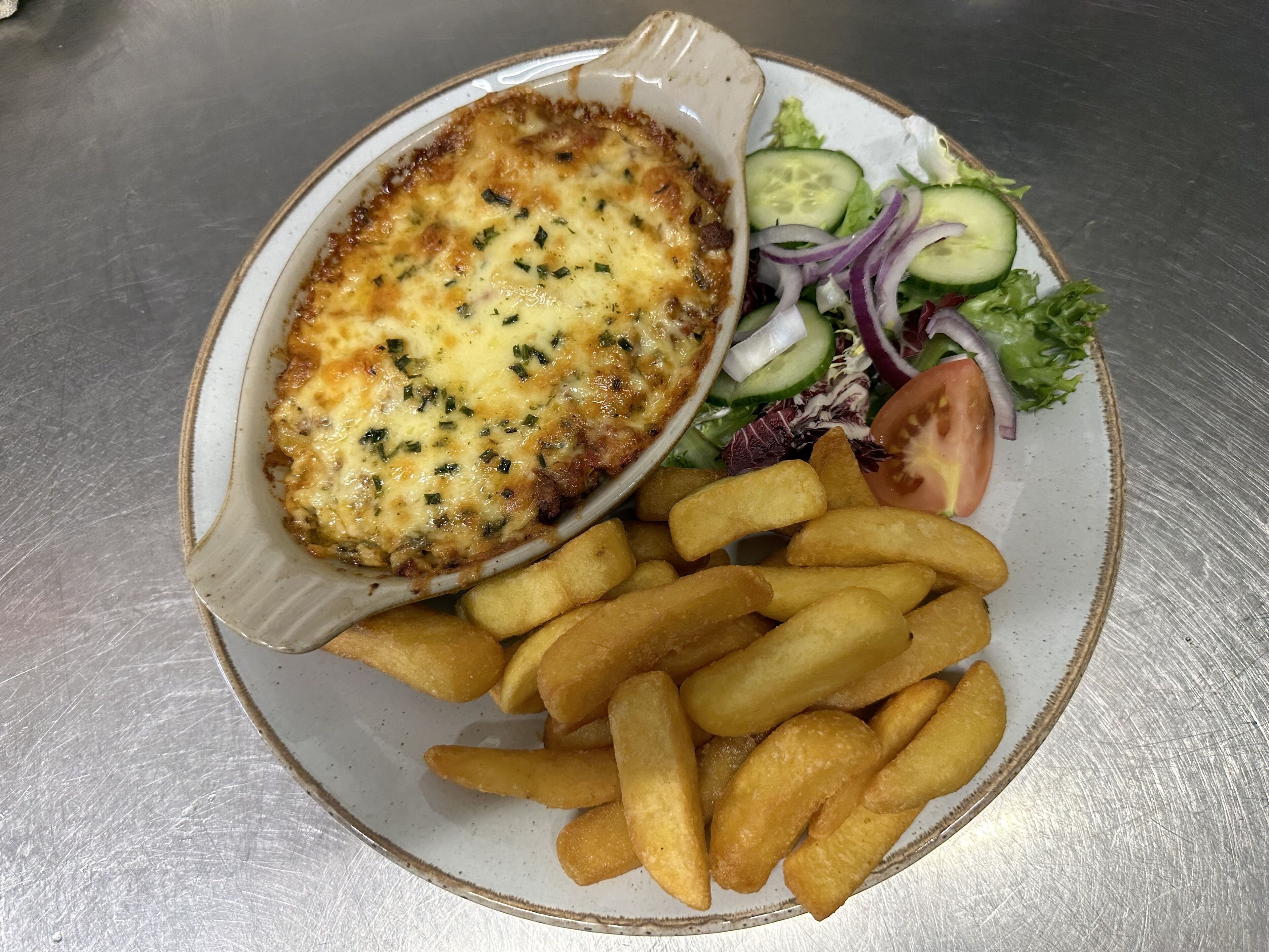A plate with a baked dish, French fries, and a side salad.