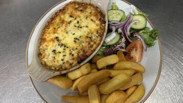A plate with a baked dish, French fries, and a side salad.