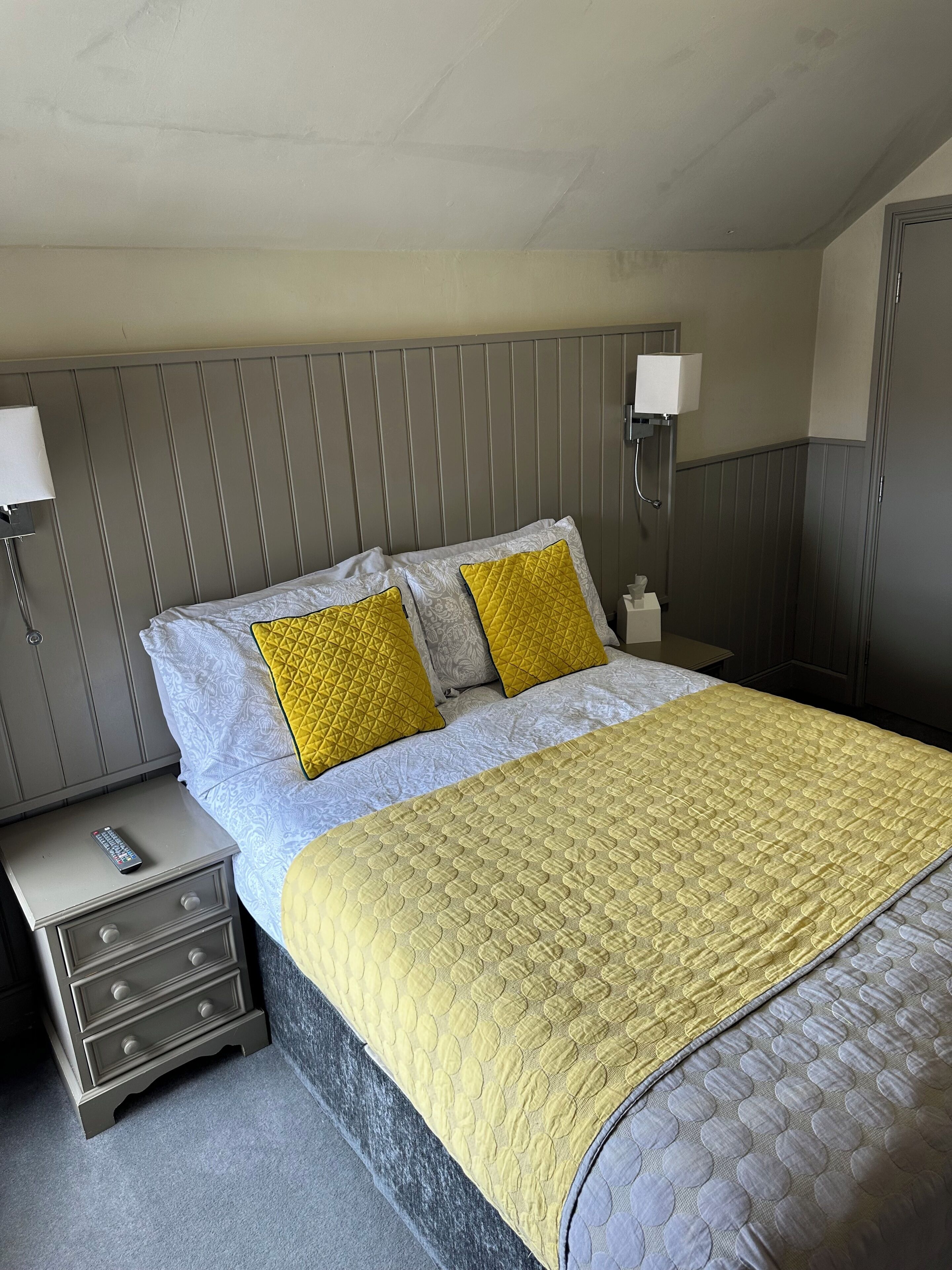 Une chambre d’hôtel avec un lit, une table de chevet, une lampe et une petite table.