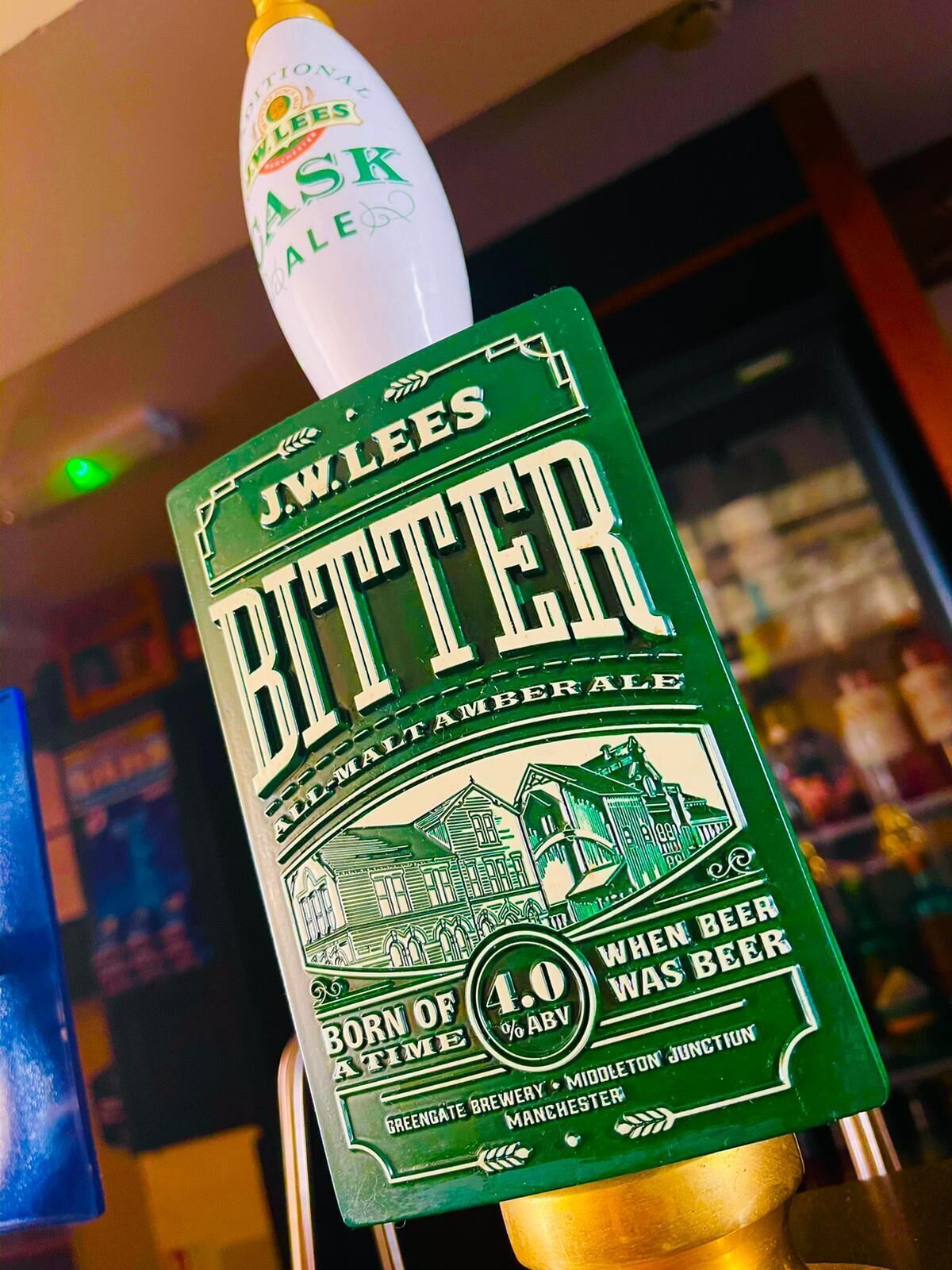 Hanet med skilt 'J.W. Lees Bitter', 'Born of Time'-logo og angivelse af 4,0% alkohol.