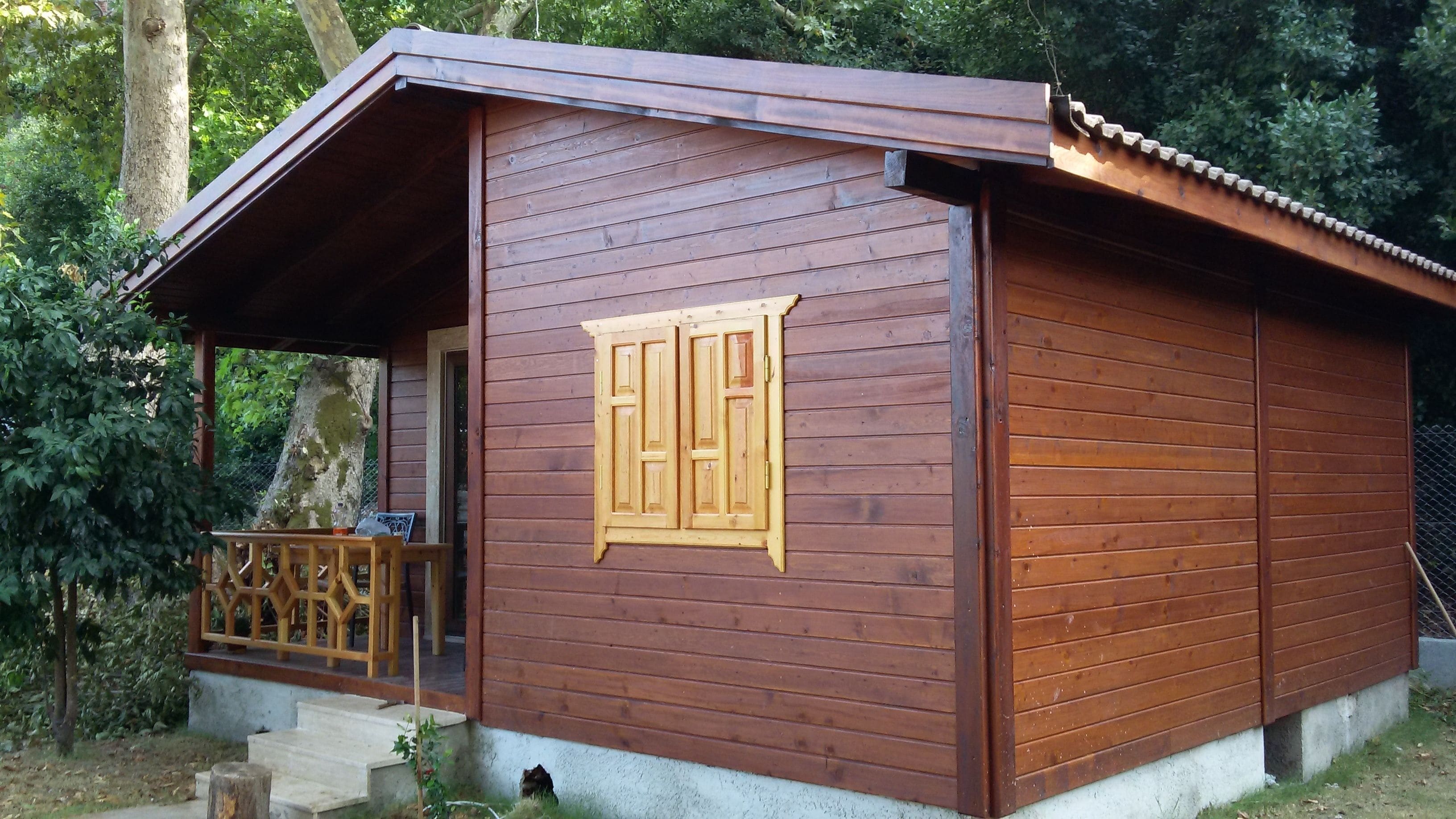 A wooden cabin with a porch, a small table, and a bench.